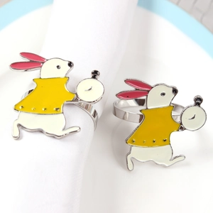 Detailed view of enamel bunny napkin rings with white and yellow outfit on table