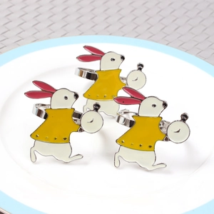 Detail of bunny napkin rings with white enamel and clock design on a ceramic plate