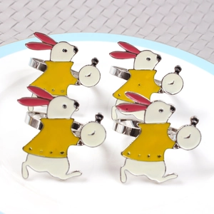 Macro shot of four rabbit-shaped metal napkin rings with pocket watch detail on a white plate