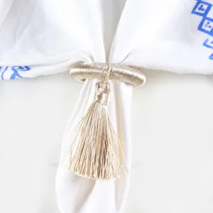 Macro shot of elegant champagne gold silk tassel napkin ring on white fabric