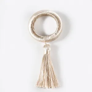 Detailed view of champagne silk tassel napkin ring with minimalist braided cord design