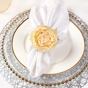 Detailed close-up of champagne peony napkin ring with realistic silk petals and green leaves
