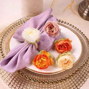 Close-up of white artificial peony napkin ring on purple linen napkin with elegant table setting