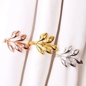 Detailed view of leaf-shaped napkin rings in gold, silver, and rose gold plating