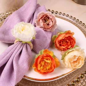Close-up of silk peony flower napkin rings in various colors on elegant tableware