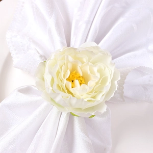Macro detail of artificial white peony napkin ring showing fabric petal texture