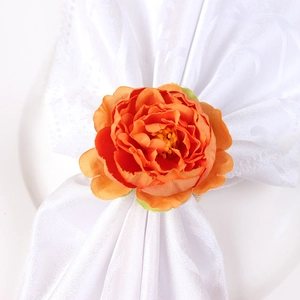 Detail of orange faux silk peony napkin ring on a white jacquard napkin for table decor