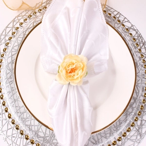 Close-up of champagne peony napkin ring on a white satin napkin for banquet table decor
