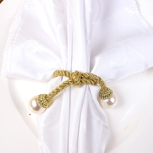 Detailed macro view of a gold twisted wire napkin ring featuring elegant white pearls