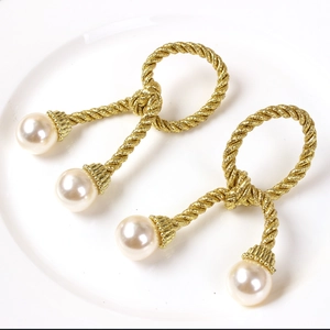 Elegant gold woven rope napkin rings with large pearl accents for holiday tables