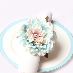 Macro detail of artificial blue and pink peony flower napkin ring on a white plate