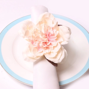 Detailed macro view of pink peony napkin ring with silk petals on a white plate