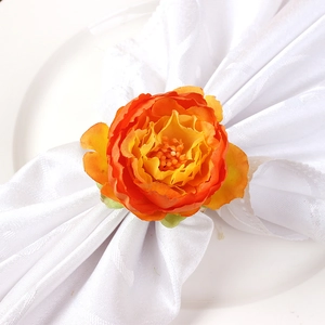 Elegant orange faux peony flower napkin ring on white textured fabric for banquet decor