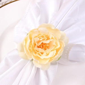 Elegant yellow artificial peony flower napkin ring on white fabric for table decor
