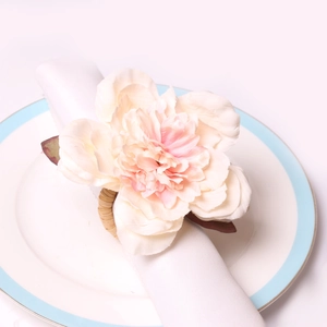 Detailed view of artificial pink peony napkin ring on a white plate for dining decor