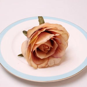 Macro shot of artificial champagne peony napkin ring with layered petals on a porcelain plate