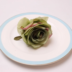 Detail shot of a vintage grey-green peony napkin ring on a white ceramic plate
