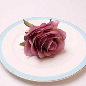 Close-up of vintage peony napkin ring in dusty rose on white ceramic plate with blue rim