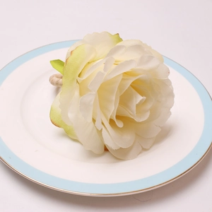 Detailed view of a white peony napkin ring set on a blue-rimmed porcelain plate
