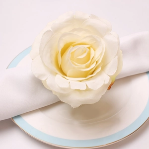 Detail view of cream artificial peony napkin ring on white linen and porcelain plate