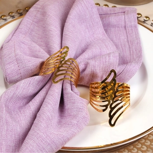 Golden feather angel wing napkin rings on purple linen napkins for luxury table decor