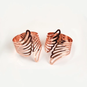 Close-up of rose gold angel wing napkin rings with intricate hollowed-out feather details