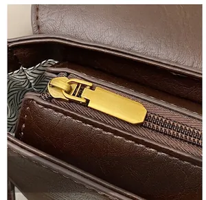 Detail of vintage brown bag showing smooth gold metal zipper and geometric pattern lining