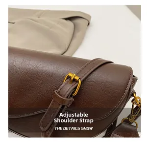 Detail of adjustable strap with vintage gold buckle on brown lychee pattern leather bag