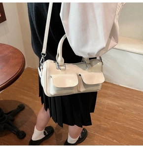 Detail of cream white Boston bag showing flap pockets and embossed logo on PU leather
