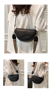 Detail of black half-moon saddle bag showing textured leather and two stylish straps