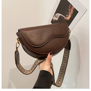 Detail of vintage brown saddle bag with textured leather and colorful woven strap