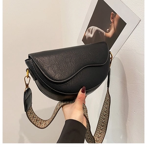 Detail of black saddle bag with textured leather and ethnic woven shoulder strap