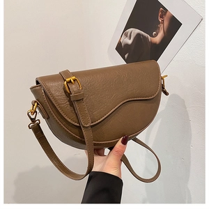 Close-up of brown faux leather saddle bag with lychee texture and gold metal buckle