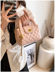 Close-up of pink quilted leather bag with gold clasp and chain strap detail