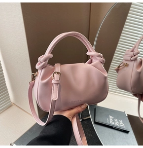 Detailed macro view of pink pleated leather handbag with knot handle and branding