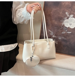 Close-up of a white glossy PU leather Boston tote bag with a heart-shaped charm accessory