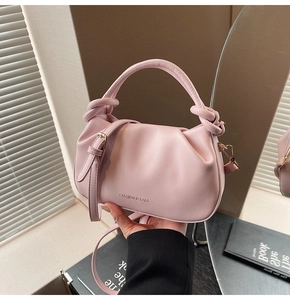 Detail of light pink pleated bucket bag featuring a knot handle and soft leather texture