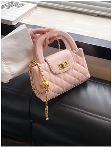 Macro shot of pink quilted PU leather bag with gold metal twist lock and chain strap