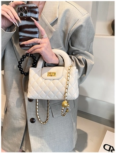 Close-up of beige quilted bag featuring a gold ball adjustable chain strap and turn-lock