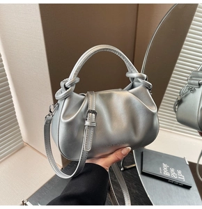 Close-up of silver pleated bucket bag with cylindrical handle and detachable strap