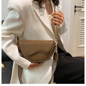 Brown leather saddle bag with vintage pleated texture and ethnic style fabric strap