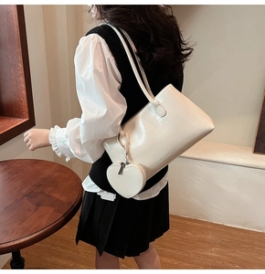 Detail of a large cream tote bag with fine leather texture and a heart-shaped coin purse