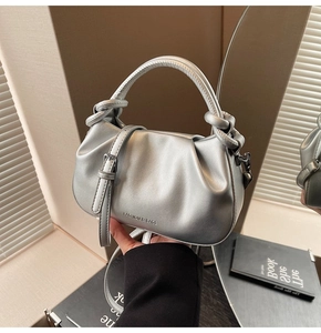 Detail showing metallic silver pleated bucket bag with knot handle and shoulder strap