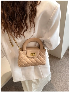 Quilted crossbody bag detail featuring elegant chain strap on model in soft beige