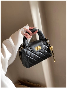 Detail of black quilted mini bag featuring golden ball chain and metallic clasp