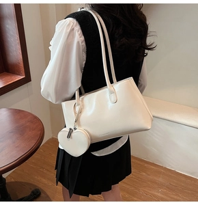 Detail of a creamy white PU leather tote bag with a small heart-shaped coin purse attachment