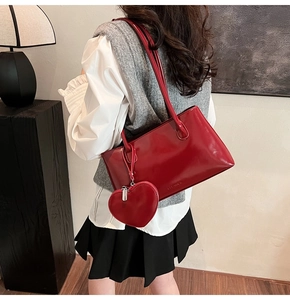 Detail of red patent leather shoulder bag with a heart-shaped coin purse charm