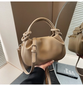 Detail view of khaki pleated bucket bag with knotted handle and fashion branding