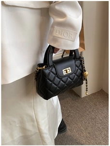 Detail of black quilted leather handbag with gold metal lock and chain strap