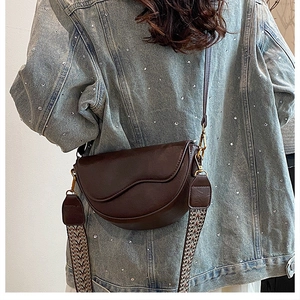 Detail view of brown saddle bag with woven strap on denim jacket outfit